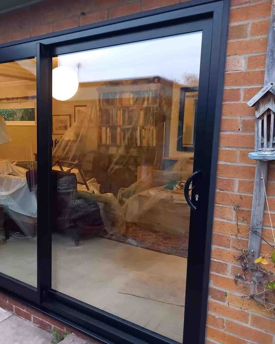 Black aluminium sliding patio door fitted into a brick rear wall