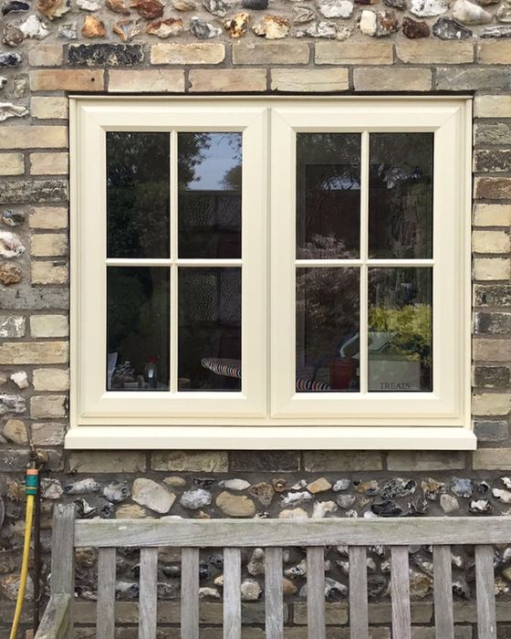 Cream timber alternative casement window set in a flint and brick wall